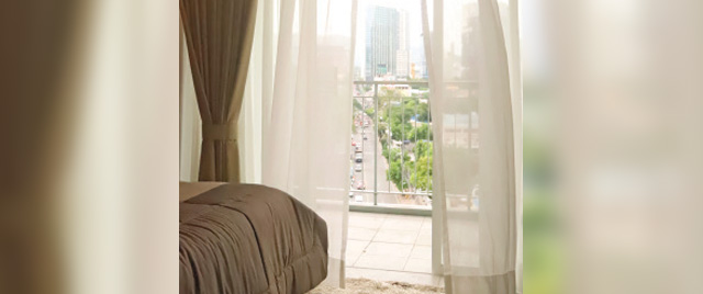 A cozy bedroom featuring a large window with a panoramic view of the city skyline.